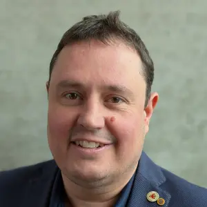 Close up portait of Sven Jeschke smiling, wearing a dark blue shirt and jacket. Photo by Julia Schwab.
